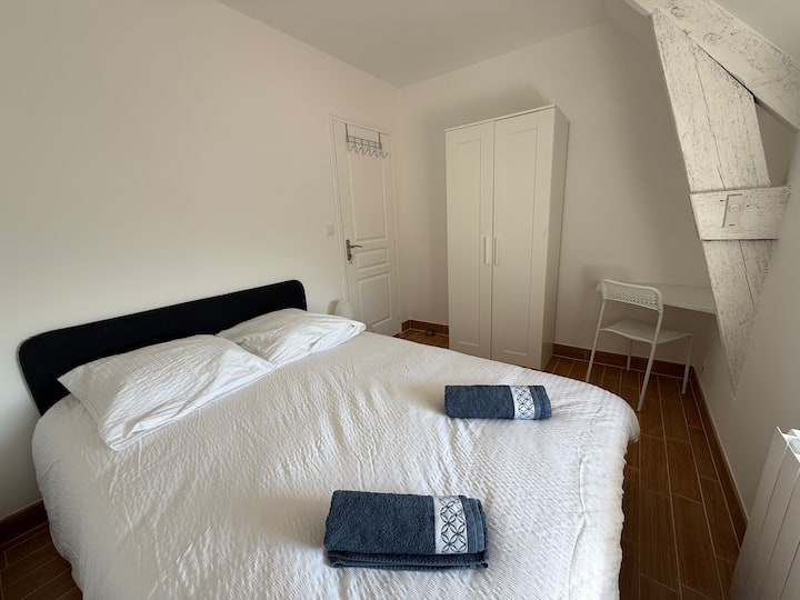 Chambre double avec lit noir, armoire blanche et poutres apparentes dans le gîte Austral à Saint-Malo