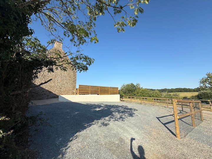 Cour en gravier du gîte Austral avec clôture en bois et vue dégagée sur les prairies près de Saint-Malo