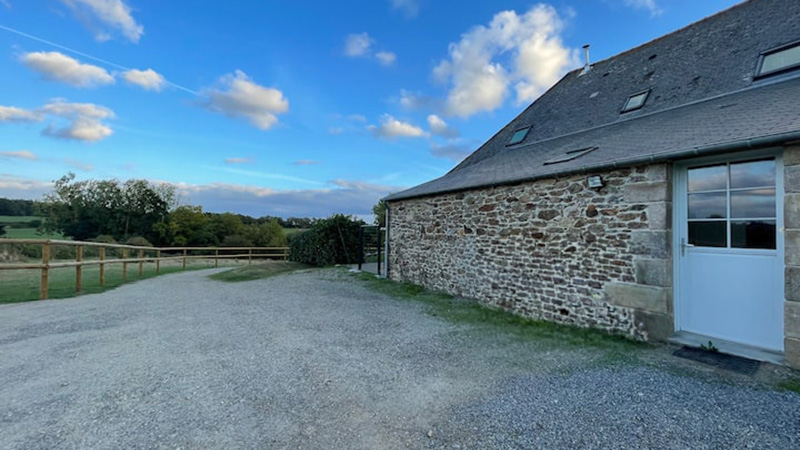 Façade en pierre du gîte Mistral près de Saint-Malo, cour gravillon et vue sur la campagne bretonne