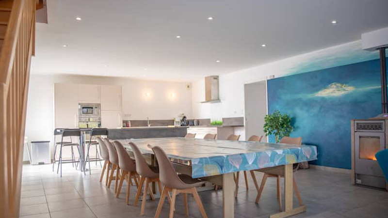 Grande salle à manger ouverte sur la cuisine du gîte Mistral, table 12 couverts et fresque murale Saint-Malo