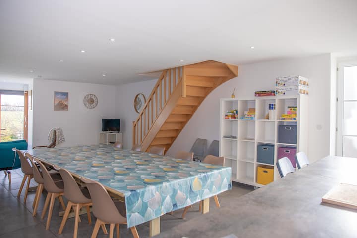 Séjour spacieux du gîte Mistral avec escalier en bois, grande table familiale et coin jeux pour enfants